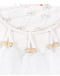 Detalle de un atrapasueños blanco con plumas, cuentas de madera y patrón de red tejida