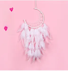 Detail of crescent moon dreamcatcher with white feathers and pearls on pink background