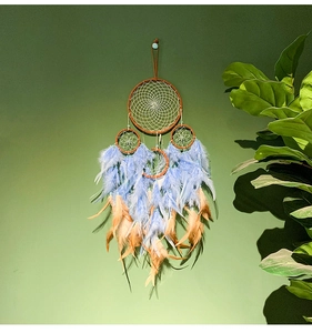 Λεπτομέρεια boho ονειροπαγίδας με μπλε και πορτοκαλί φτερά σε πράσινο τοίχο