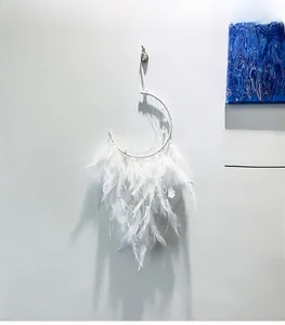 Close-up of crescent moon dream catcher with white feathers and elegant woven netting