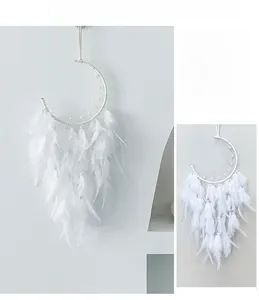 Close-up of a white moon-shaped dreamcatcher with feathers and pearl bead accents