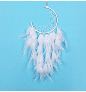 Detailed view of white moon dreamcatcher with feathers and pearls on blue background
