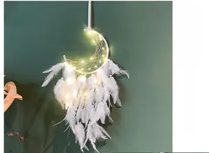Moon-shaped white dream catcher with feathers and warm LED lights on a dark wall