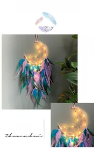 Detail of moon-shaped dream catcher with teal and purple feathers and warm LED lights