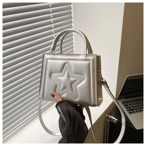 Detail of silver handbag featuring a 3D star pattern with dual handles and long strap