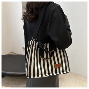 Striped canvas tote bag with black handles and fashion patch shown on a model