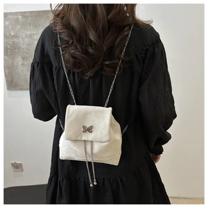 Detailansicht eines weißen Mini-Rucksacks mit Schmetterlings-Schnalle und Kettenfransen