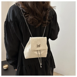 Detail des cremefarbenen Mini-Rucksacks mit Silber-Schmetterling und Kettenzug