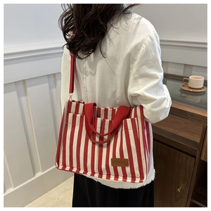Detail of red and white striped canvas tote bag with fashion label and shoulder strap