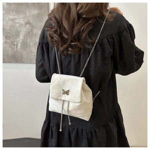 Close-up of a white velvet mini backpack featuring butterfly buckle and metal chain detail