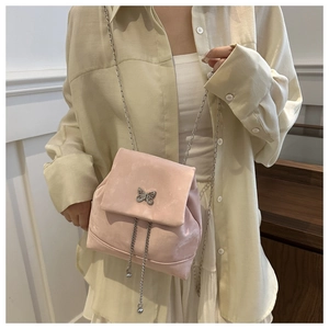Close-up of pink velvet mini bag with metal butterfly buckle and tassel chain details