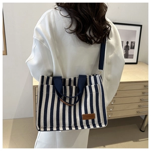 Detailed back view of a blue and white striped canvas tote bag worn by a model