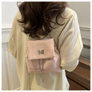 Detail of pink leather backpack featuring a silver butterfly charm and chain tassels