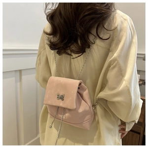 Detail of pink velvet mini backpack featuring silver butterfly charm and chain strap