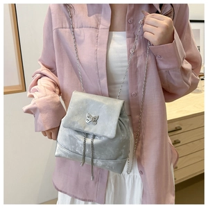 Detail of silver velvet small backpack featuring elegant butterfly buckle and chain strap