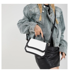 Detail showing the contrast stitching on a chic black and white leather shoulder bag