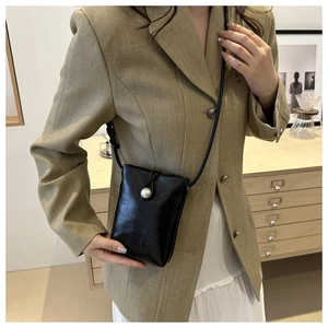 Mini sac bandoulière en cuir noir avec fermoir perle sur mannequin en costume marron