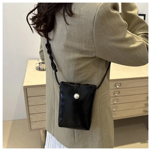 Dettaglio borsa porta cellulare in pelle nera con chiusura a perla e tracolla intrecciata