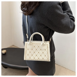 Détail du sac bandoulière crème avec surpiqûres losanges et rivets en cœur dorés