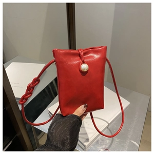 Dettaglio macro della mini borsa rossa in ecopelle con chiusura a perla e tracolla