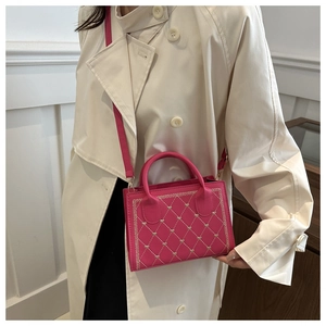 Vue macro du petit sac carré rose rouge avec surpiqûres en cœur et attaches dorées