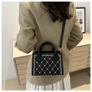 Détail d'un sac à bandoulière noir matelassé avec accents de cœur sur une tenue décontractée