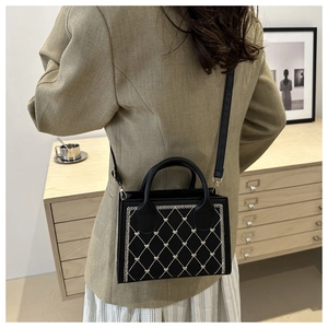 Détails d'un sac bandoulière noir matelassé avec broderie cœur porté par un mannequin
