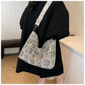 Detail of bohemian geometric woven crossbody bag featuring a wide decorative shoulder strap