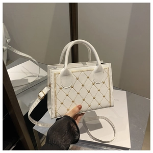 Détail du sac bandoulière blanc matelassé avec broderie cœur dorée et accents métalliques