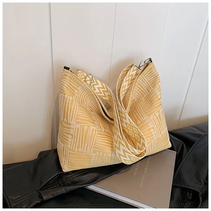 Detail of yellow and white geometric woven tote bag with a wide knitted shoulder strap