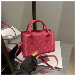 Détail du sac bandoulière matelassé rose rouge avec clous en cœur dorés et poignée lisse