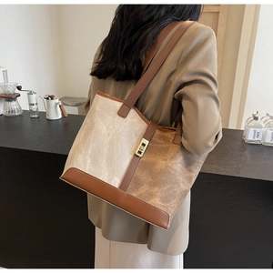 Close-up of a stylish two-tone tote bag in cream and brown with gold metallic buckle detail