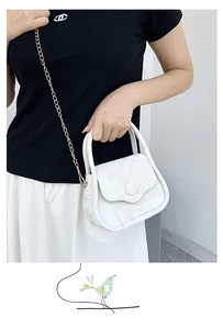 Detail of marble pattern handbag with golden chain strap on model in black and white