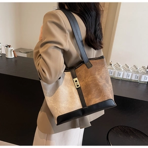 Detail of retro tote bag with brown patchwork, black leather trim and gold swivel lock