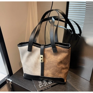 Detail of a large beige and brown tote bag featuring a golden metallic twist-lock closure