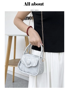 Detail of silver marble texture crossbody bag with elegant gold chain and magnetic closure