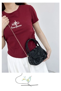 Chic black marble texture crossbody bag with gold chain strap shown on model shoulder
