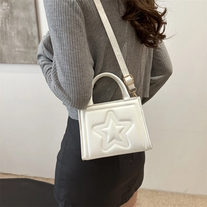 White mini handbag with star embossed design and adjustable crossbody strap on model