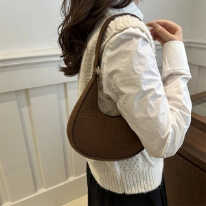 Brown faux crocodile crescent underarm bag with gold hardware shown on a model