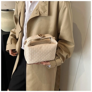 Close-up of cream woven handbag featuring a gold rectangle buckle and cross-mesh texture