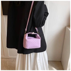 Close-up of lilac crossbody pillow bag with textured grid pattern and gold hardware