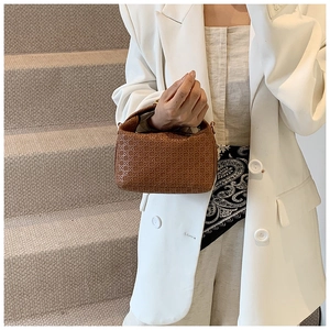 Close-up of brown woven texture and integrated handle on a stylish faux leather handbag