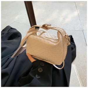 Detail of off-white woven texture shoulder bag with gold metal buckle and handle