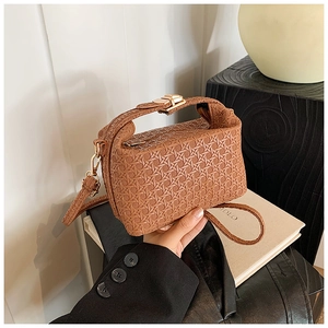 Detail of brown woven leather texture on a compact pillow bag with gold metal clasp