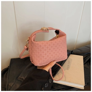 Detail of pink woven texture handbag with golden metal lock shown in lifestyle scene