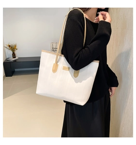 Detail of white striped tote bag with khaki leather handles and central brand patch