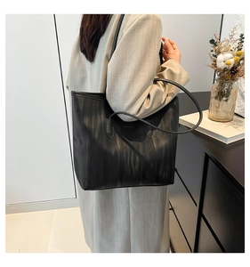 Detail of black tote bag featuring vertical stripes and slim shoulder straps