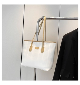 Close-up of a white tote bag with vertical texture and brown shoulder straps