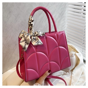 Detalle de bolso acolchado rojo rosa con textura de concha y bufanda de seda en el asa