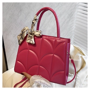 Detalle del bolso acolchado fucsia con elegante pañuelo de seda estampado en el asa